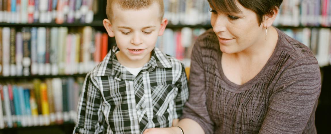 Woman and Child reading book in library