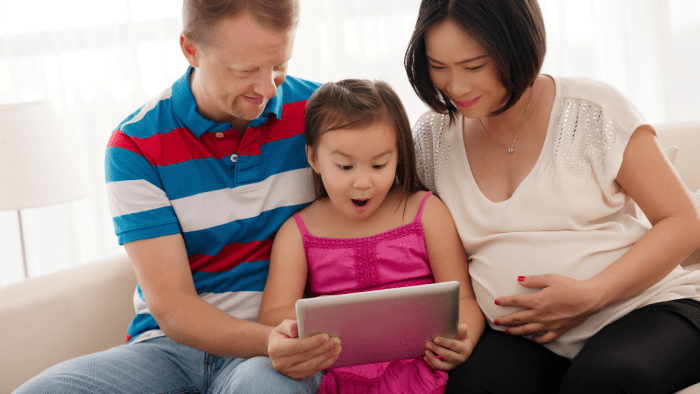 Three person family looking at tablet with interest.